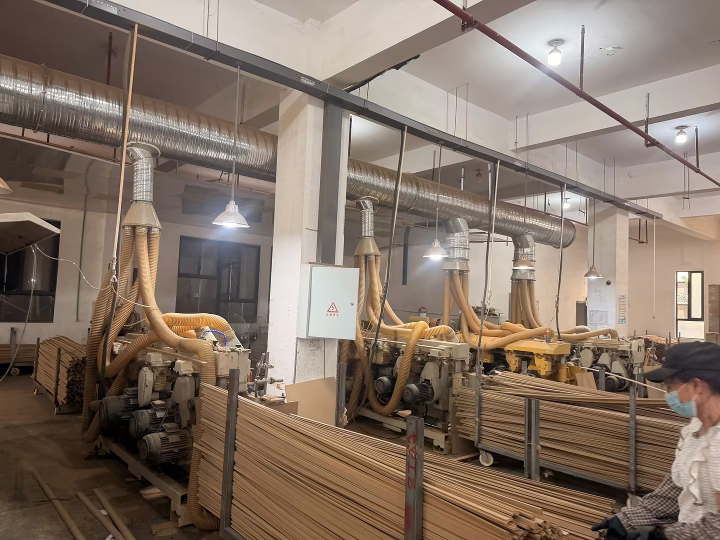 Wooden frame profiles beside processing machinery and dust-extraction ducts.