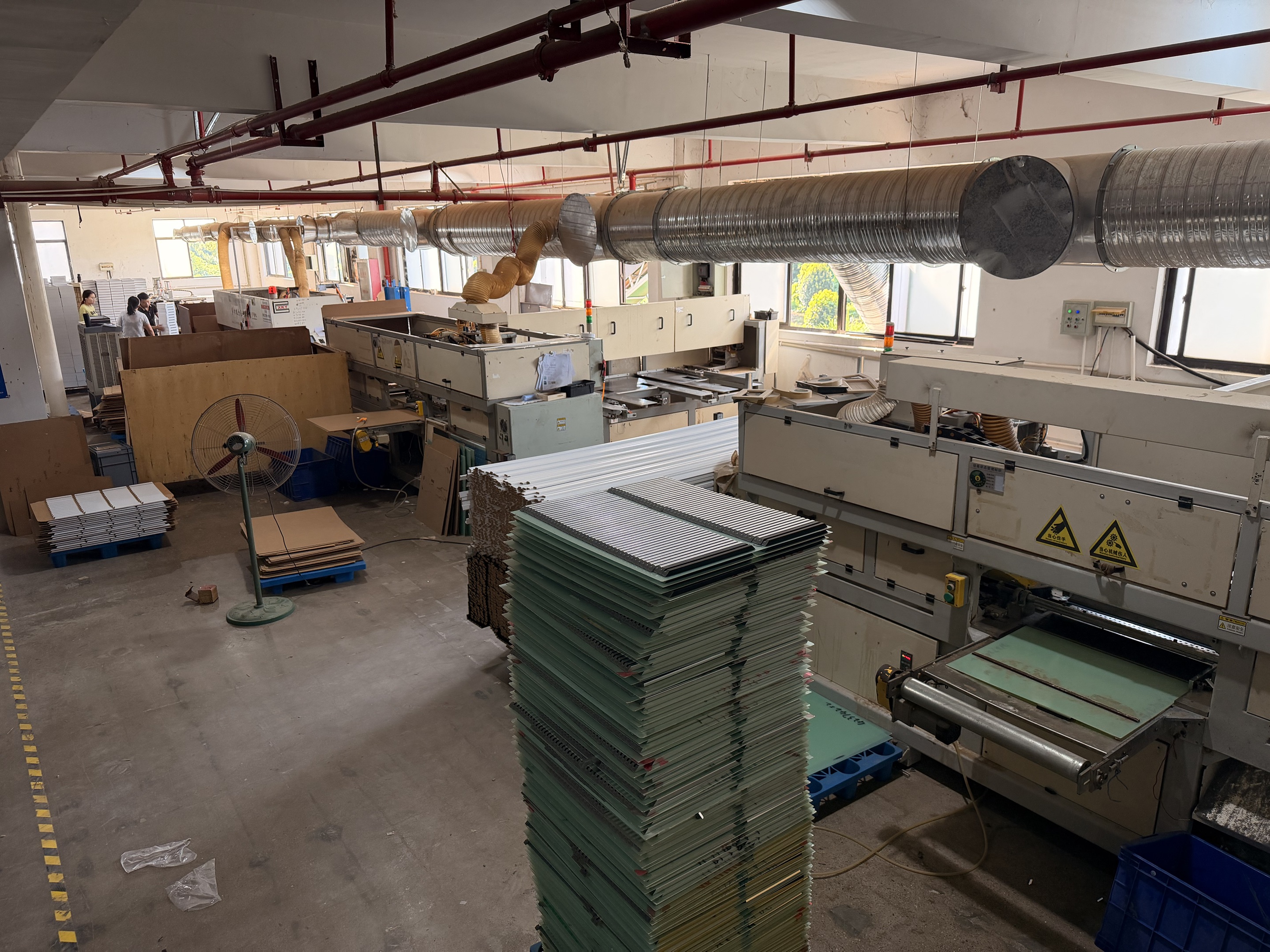 Workshop machinery, extraction ducts and stacks of panel components in the supplied factory photograph