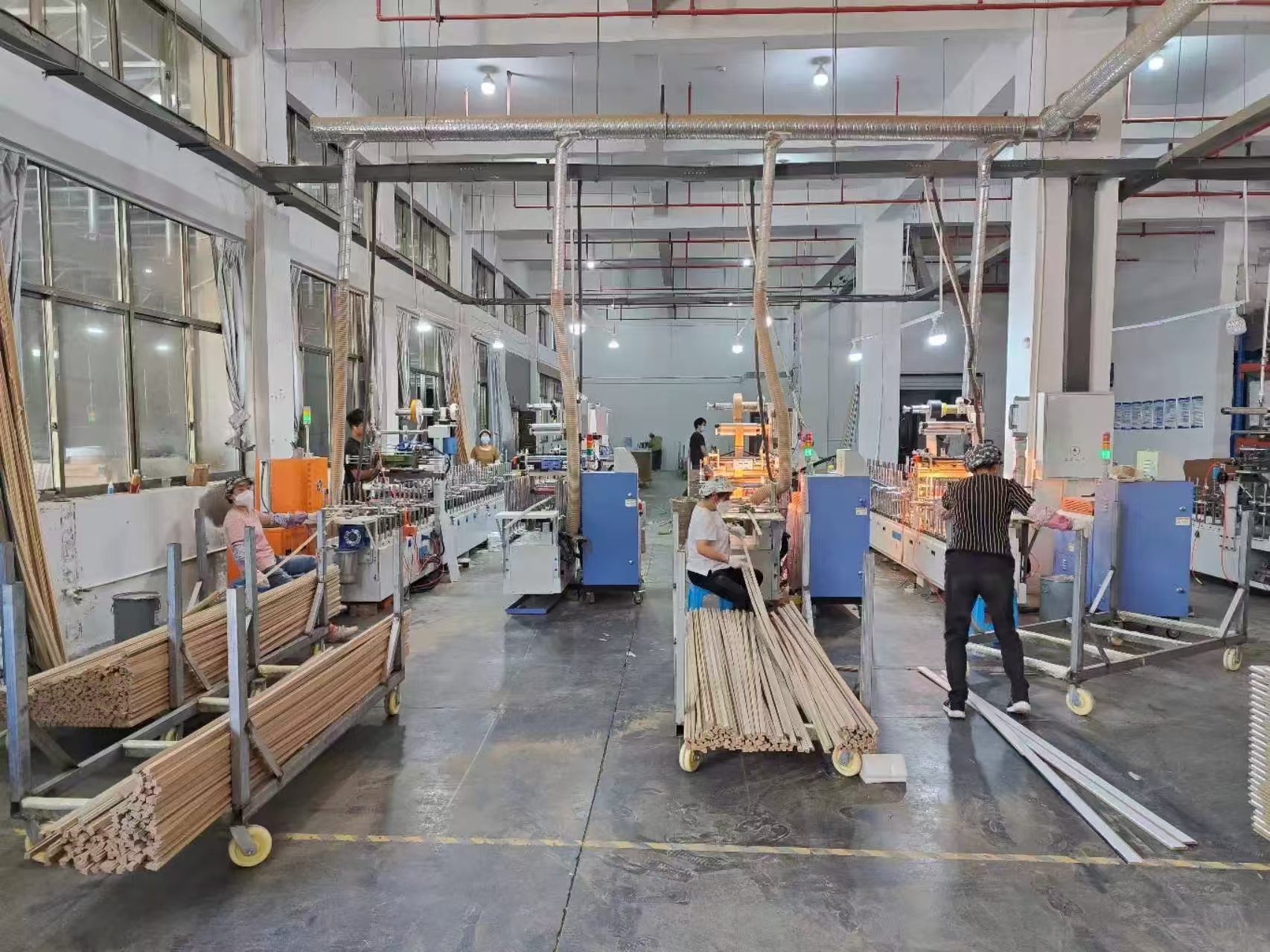 Operators, processing equipment and trolleys of frame profiles in the workshop.